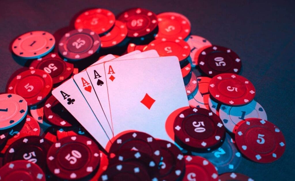 A stack of ace playing cards laying over casino chips.