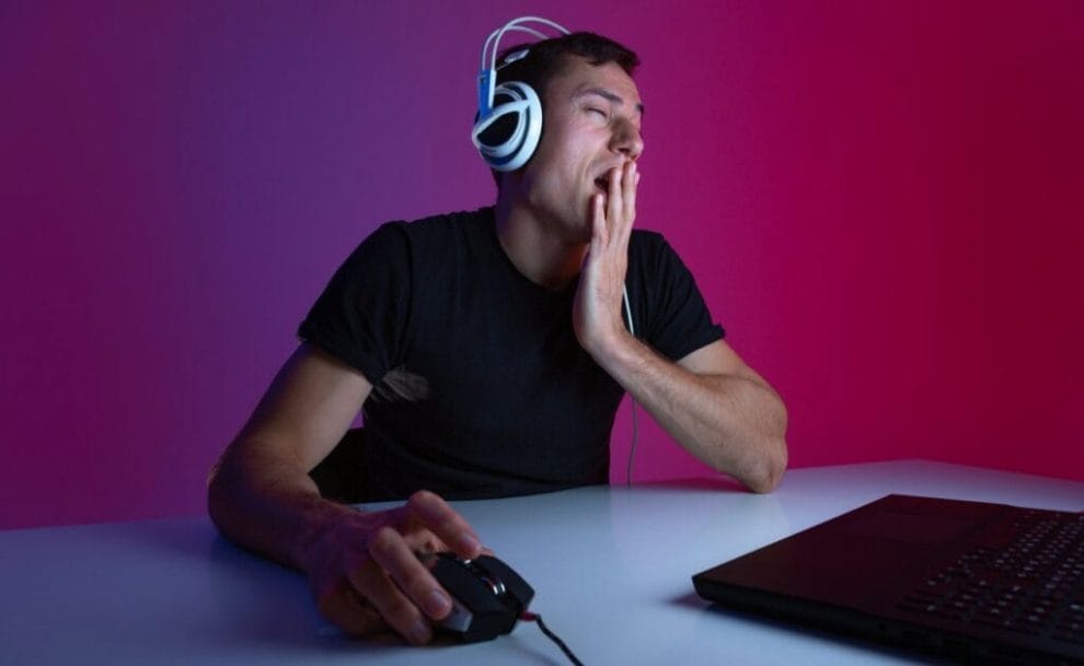 A gamer yawning while using their laptop.