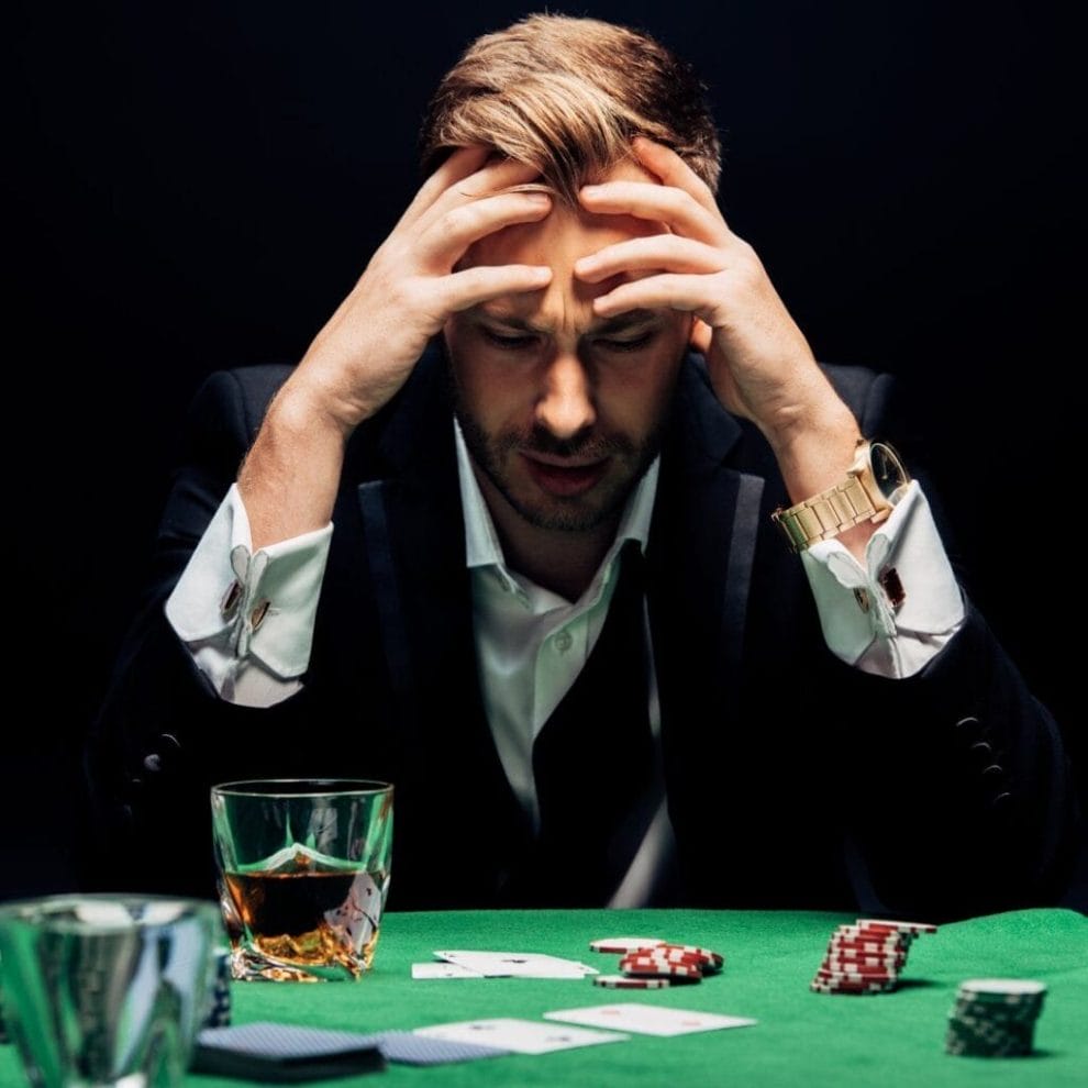 A poker player with their head in their hands.
