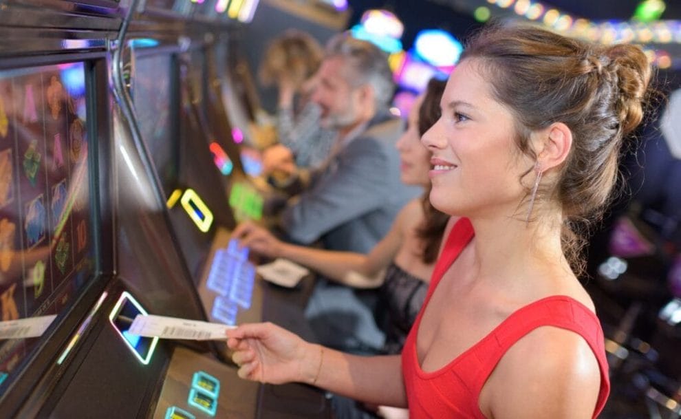 A person in a red dress playing a slot machine.