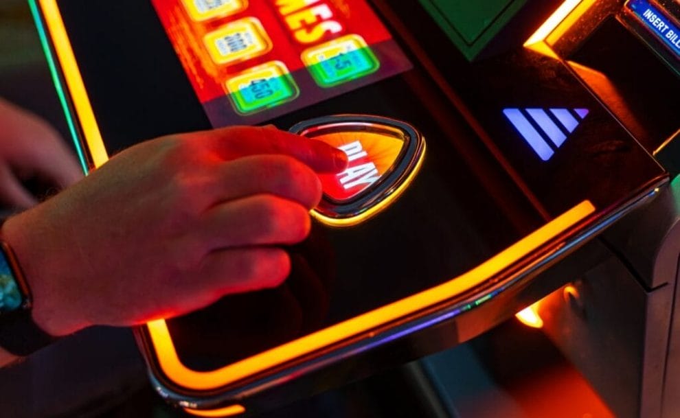 A person about to hit the play button on a slot machine.
