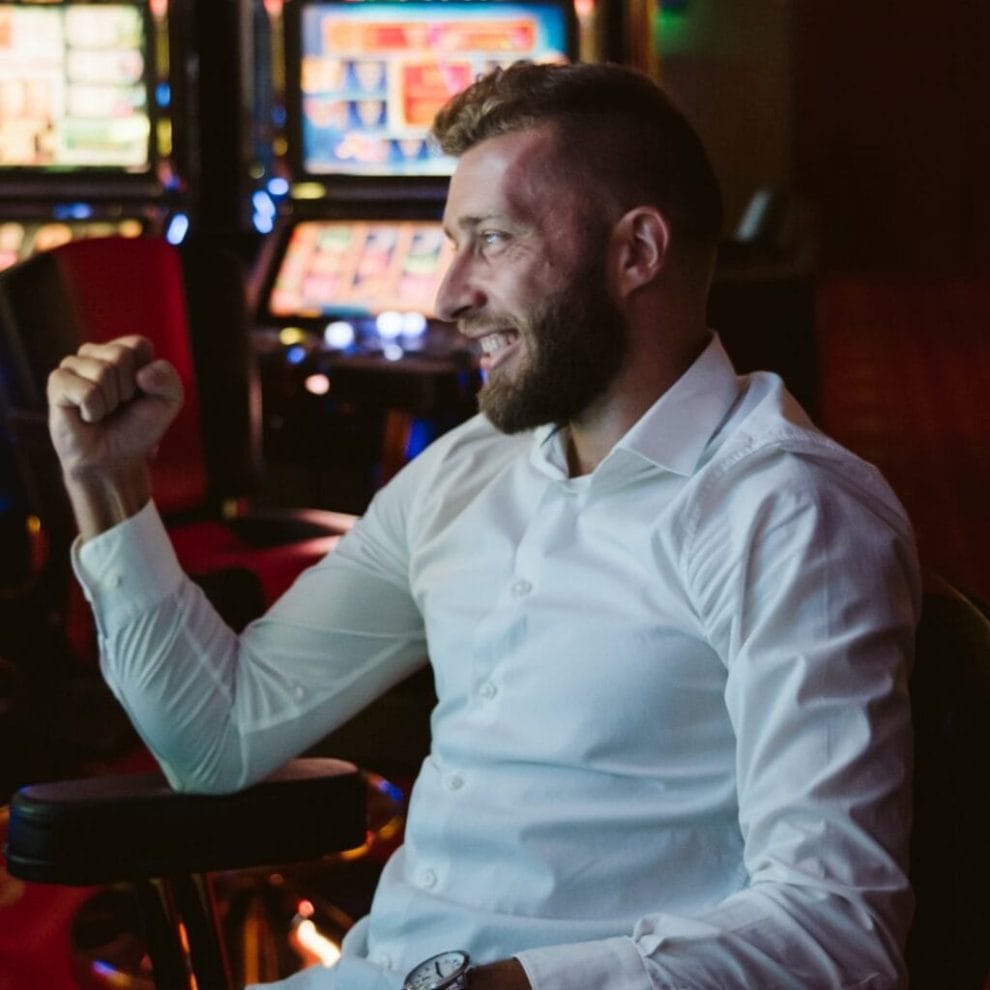 A man celebrating a win in a casino with slot machines.