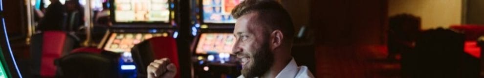 A man celebrating a win in a casino with slot machines.
