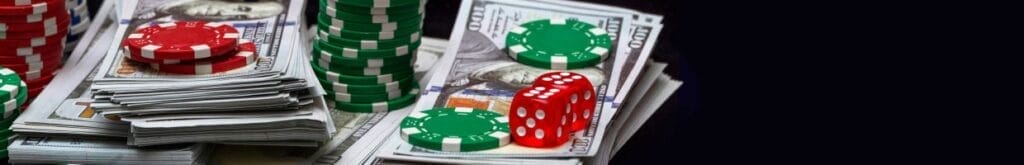 Small stacks of poker chips and two red, six-sided dice on top of stacks of cash against a black background.