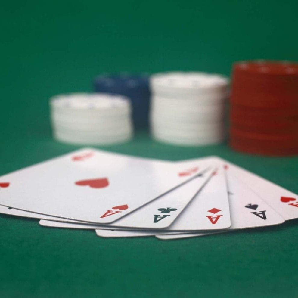 Five aces on a poker table with poker chips in the background