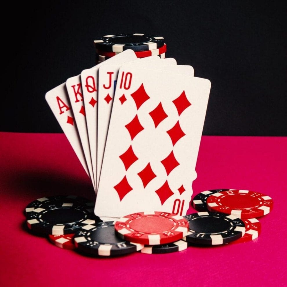 A royal flush leaning against a stack of black and red poker chips.