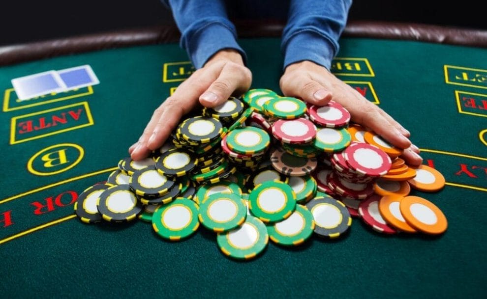 A poker player pushing all of their poker chips toward the center of the casino game table.