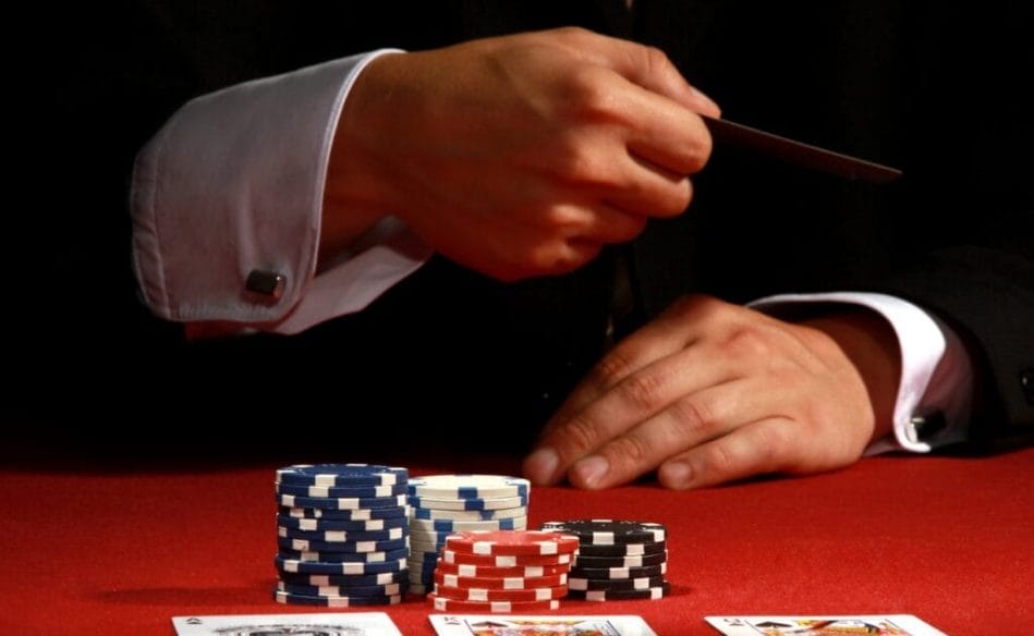 A poker player about to toss their cards into the center of the poker table. 