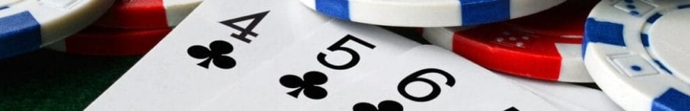 A close-up of poker cards next to scattered poker chips. The cards visible are 4, 5, and 6 of clubs.
