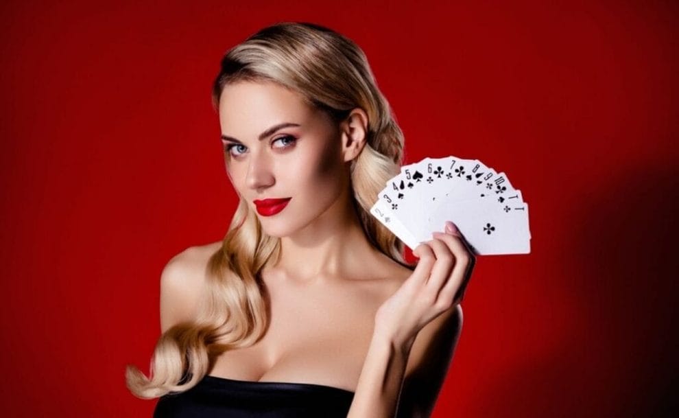 A woman wearing red lipstick holding up a stack of fanned out playing cards.