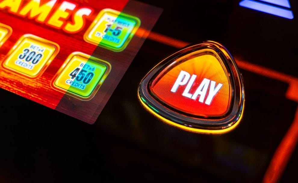 A close up of a “play” button on a slot machine.