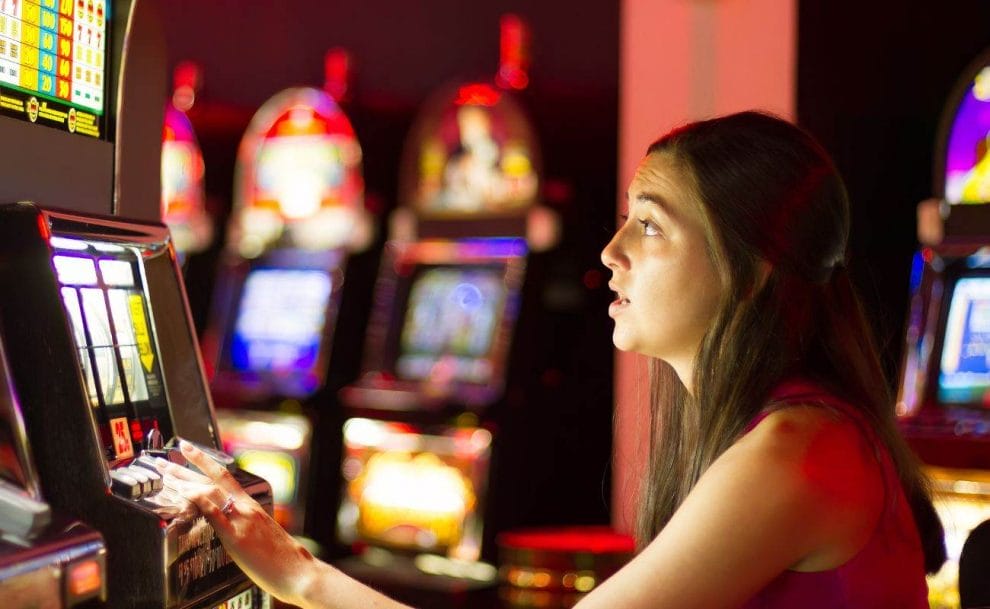 A woman with a focused look, playing a slot game, in a casino. 