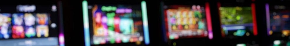 A blurred image of a row of slot machines in a casino.