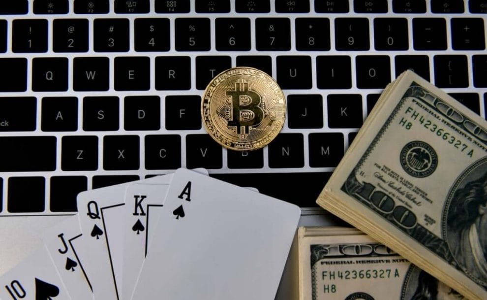 Bitcoin, dollar bills, and playing cards on a laptop keyboard