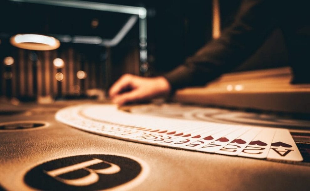 A dealer spreads out a deck of cards on a casino table while shuffling them.