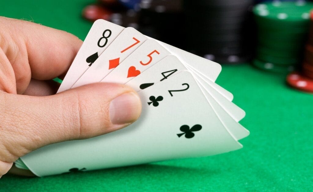 A poker player looks at their five-card poker hand. They hold an 8 of spades, a 7 of diamonds, a 5 of hearts, a 4 of spades, and a 2 of clubs.