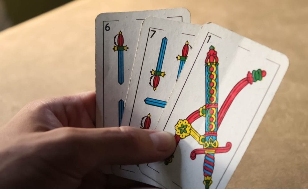 Hand holding Spanish truco playing cards