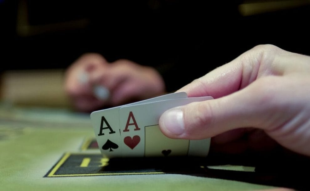 A poker player looks at their two hole cards. They have two aces.