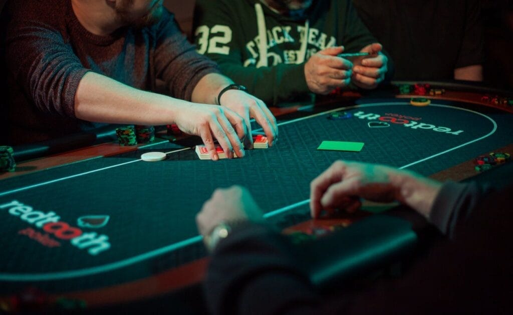 A group of friends seated around a poker table, preparing to play.