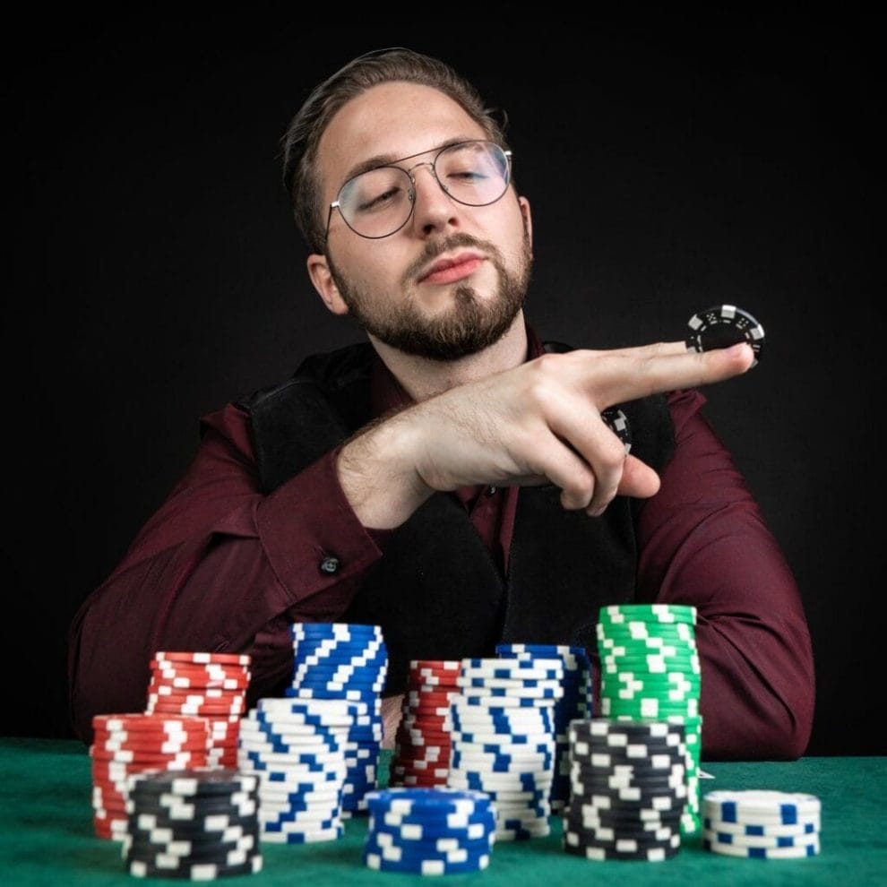 A poker player looks at a poker chip they have pinched between their middle and index fingers.