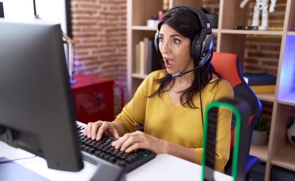 A person wearing headphones looks at their computer with a surprised expression.