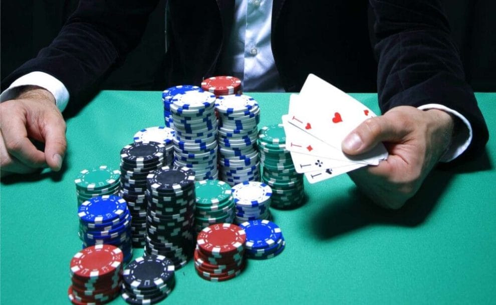 A person holding poker cards on a green felt table with casino chips.