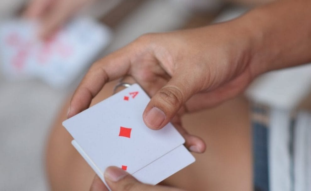 Hands holding two playing cards at a poker game.