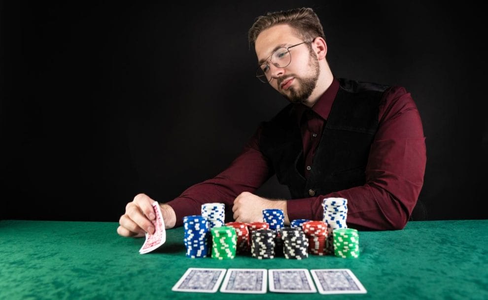 A poker player checking their playing cards at a poker table.