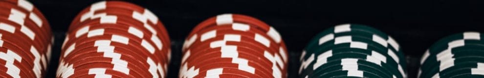 Red and black casino chips against a black background.