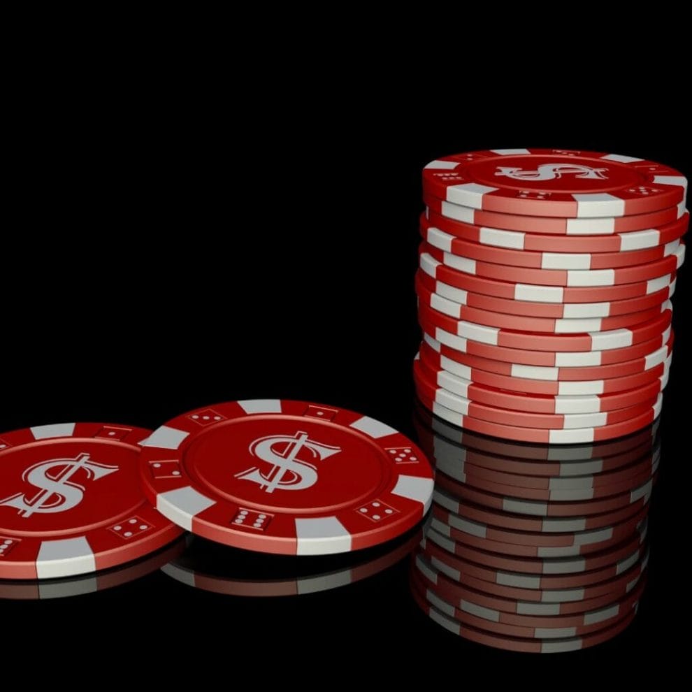Red and white casino chips on a black surface.