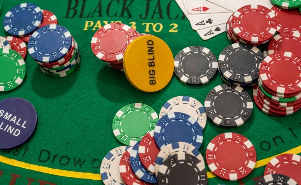 Blackjack blind chips and casino chips on a green felt table.