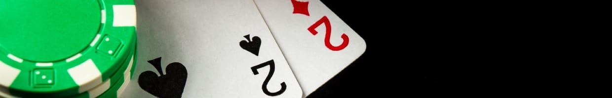 Two playing cards with green casino chips on a black surface.