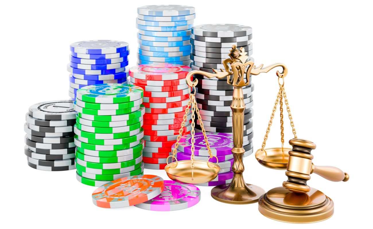 Stacks of casino chips, a balancing scale, and a judge’s gavel on top of a sound block, all against a white background.