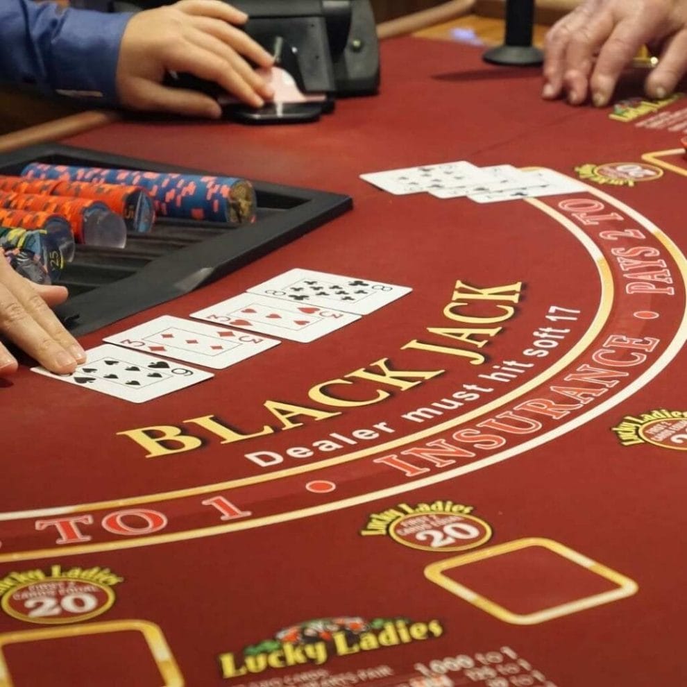 Red felt blackjack table with croupier laying out cards.