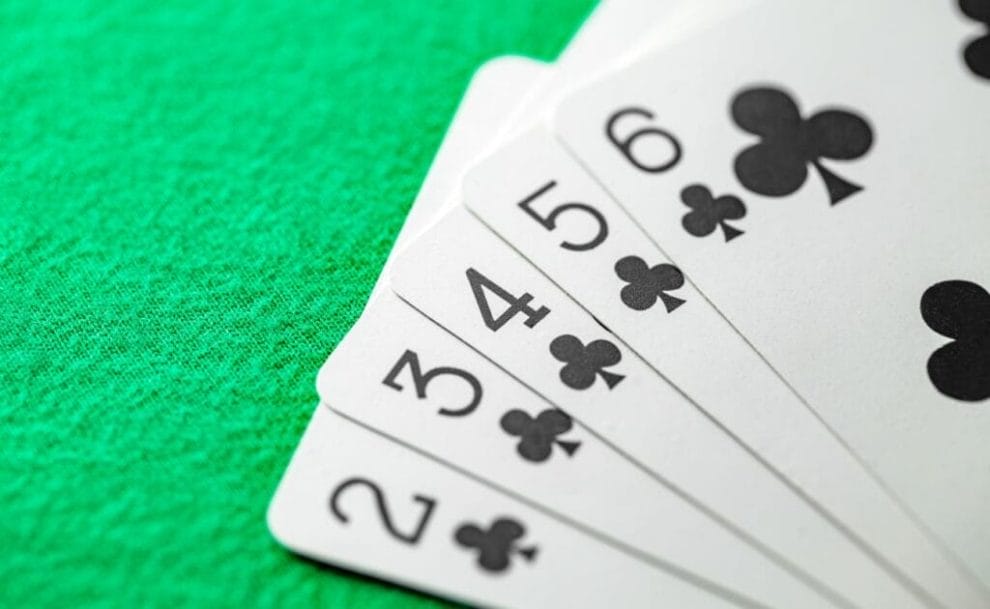 A two of Spades, a three of Spades, a four of Spades, a five of Spades, and a six of Spades, arranged on a poker table.