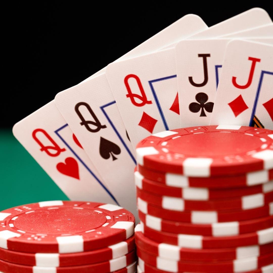 A Queen of Hearts, a Queen of Spades,a Queen of Diamonds, a Jack of Clubs, and a Jack of Diamonds, placed behind stacks of red poker chips.