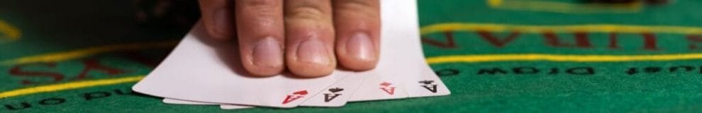 A person placing four kinds of Aces down on a poker table.