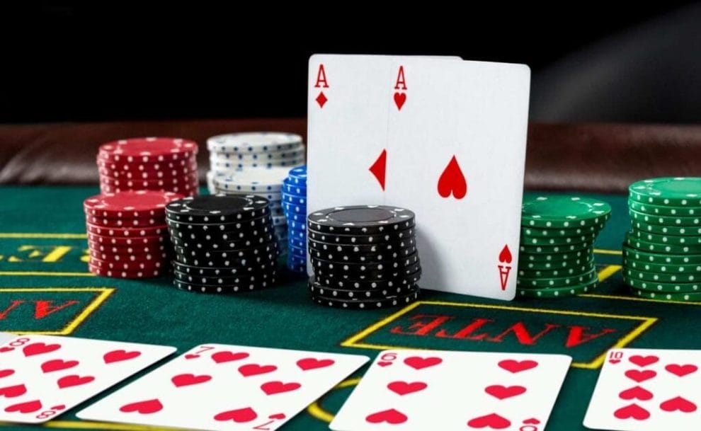 Two Ace cards balancing against casino chips on a blackjack table. 
