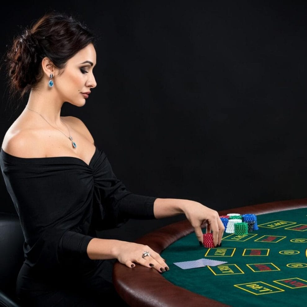 A woman sitting at the poker table holding casino chips.