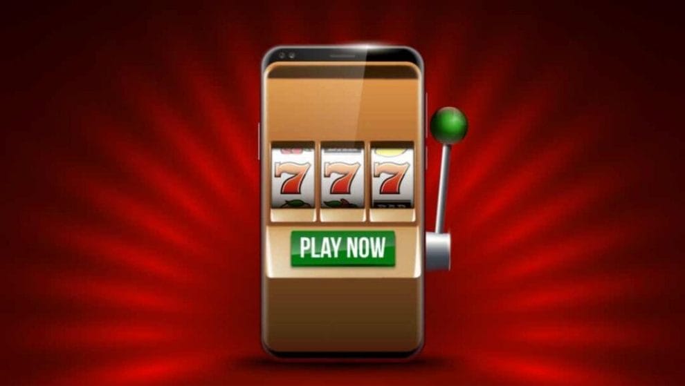 A smartphone with online slots and the 777 jackpot symbols on it on a red background.