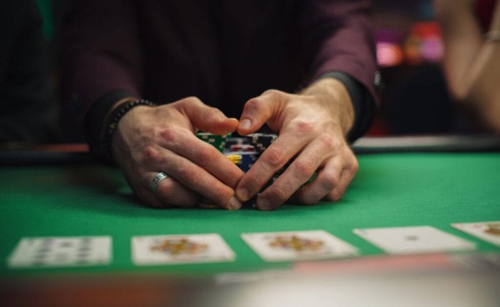 A poker player pulling stacks of poker chips towards themselves.