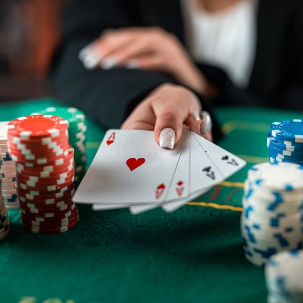 A player holding out 4 aces between multiple stacks of poker chips.