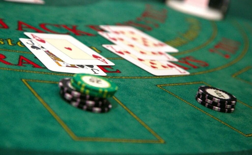 A green blackjack table with casino chips and playing cards.