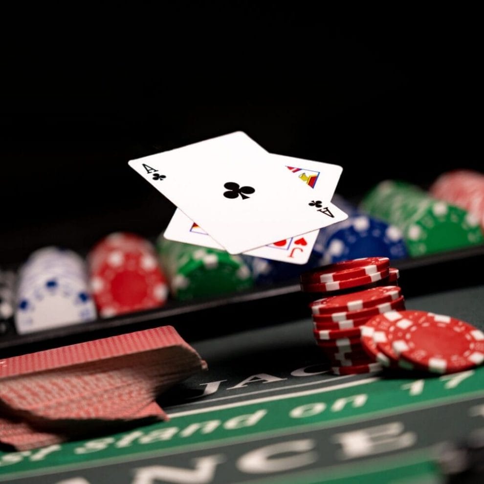 A blackjack table with casino chips and playing cards in the air.