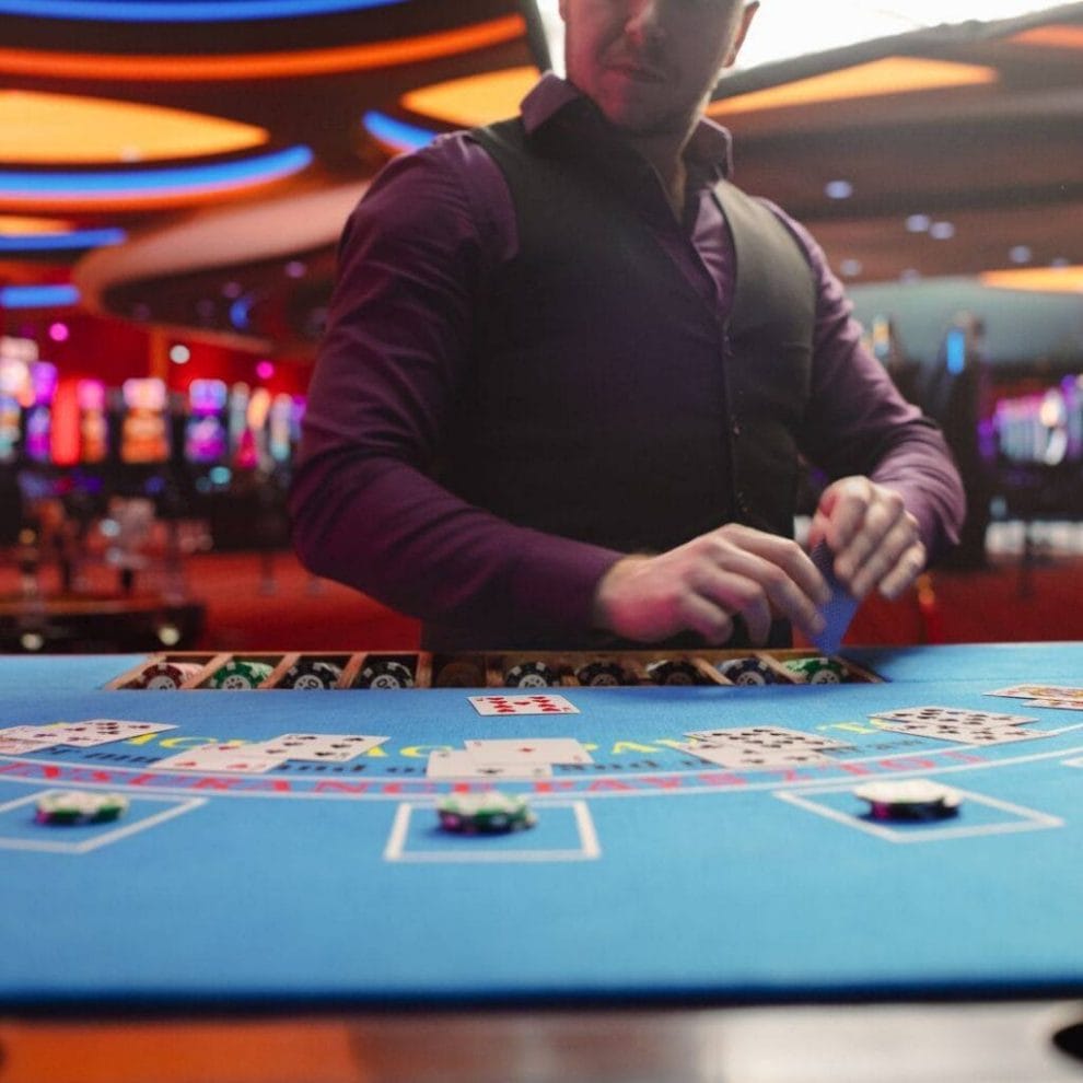 A poker dealer in a casino, behind a poker table, dealing out cards.