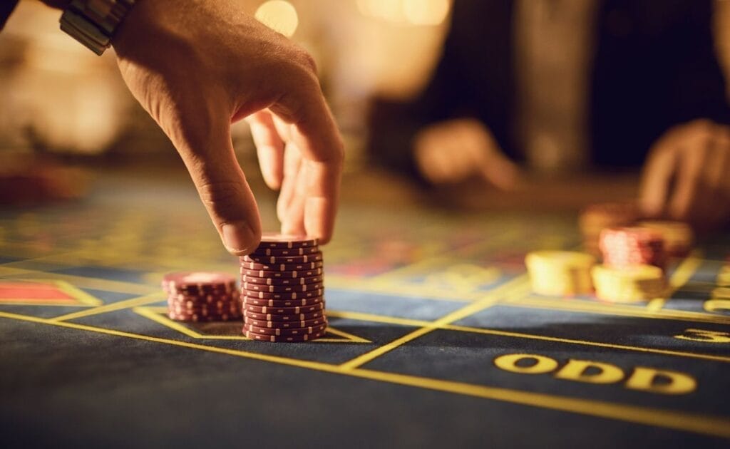 A closeup of a player adding chips to his chosen betting space on the roulette table.