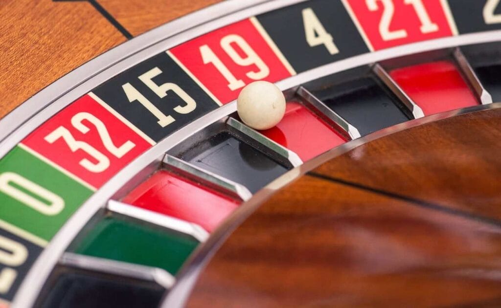 An extreme closeup of a roulette wheel with the ball in the red 19 section.