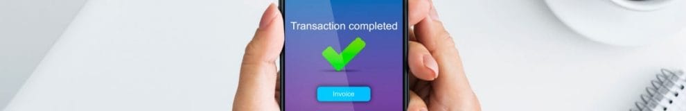 A green tick on a mobile phone displaying “transaction complete.”