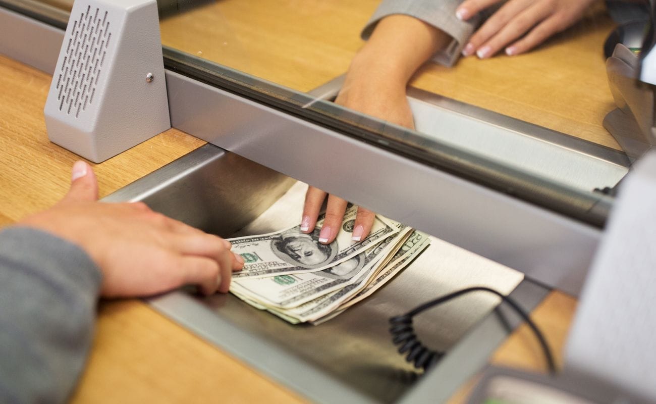 A person passing cash to a cashier.