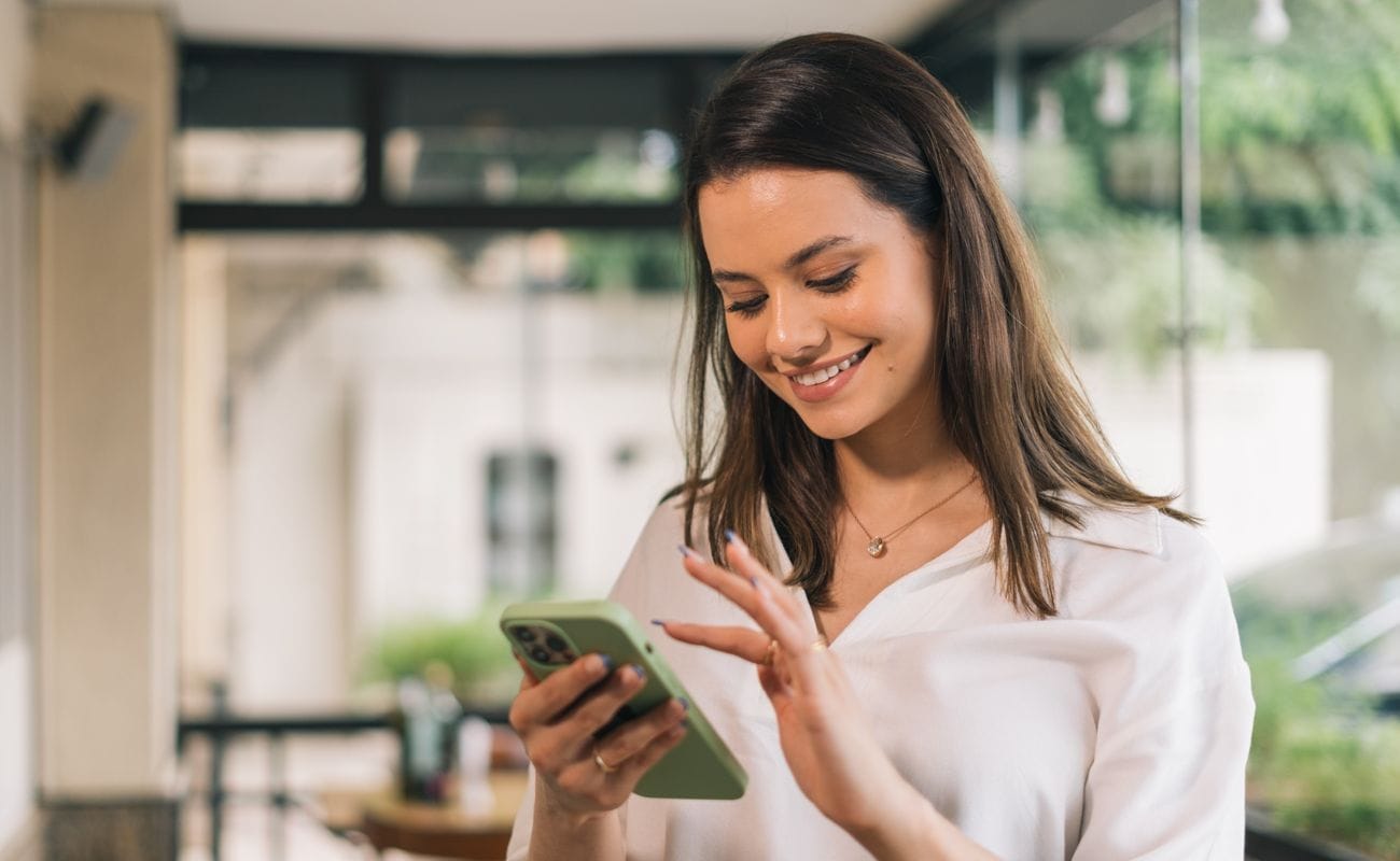 A person smiling while using their smartphone.